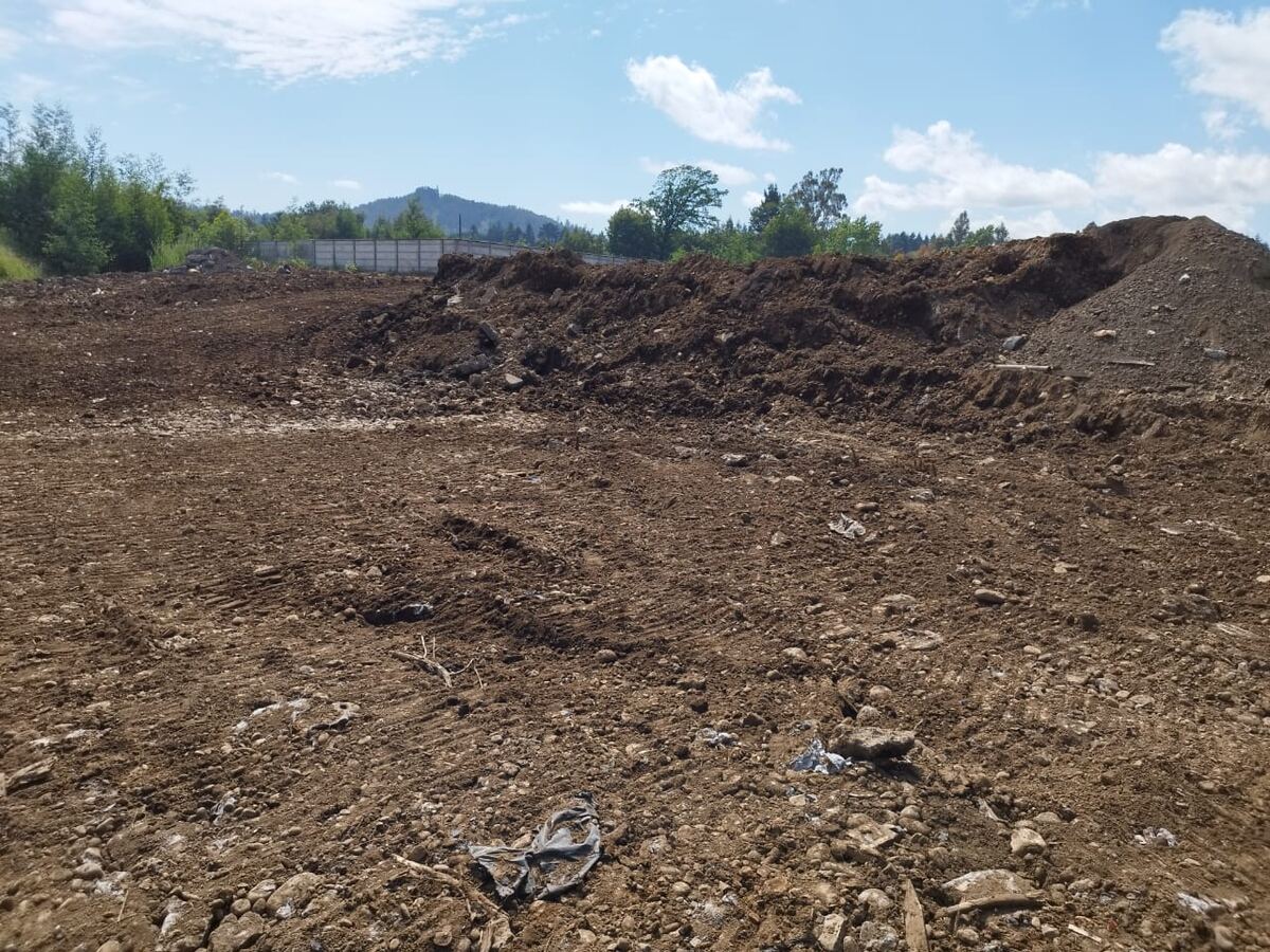 Foto real: terreno nivelado con cierre perimetral y cerro de fondo