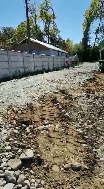 Foto real: camino de acceso con ripio compactado y huellas de neumático