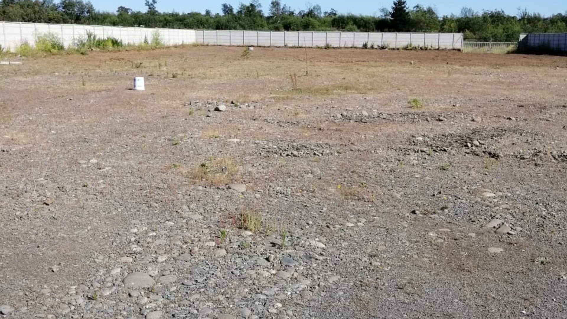 Foto real: vista panorámica del terreno con relleno de ripio compactado y cierre perimetral